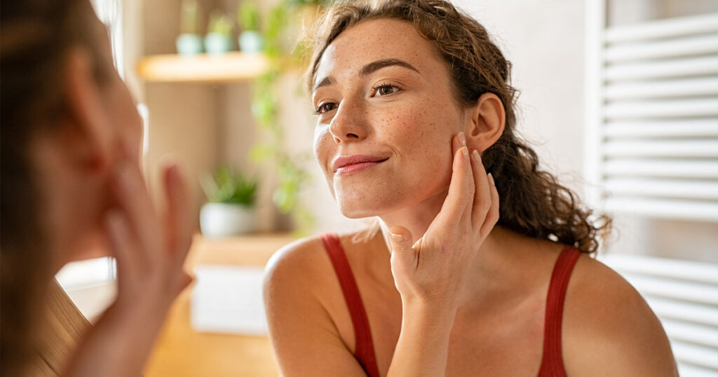 Woman touching her face in the mirror - Fat Transfer to Face